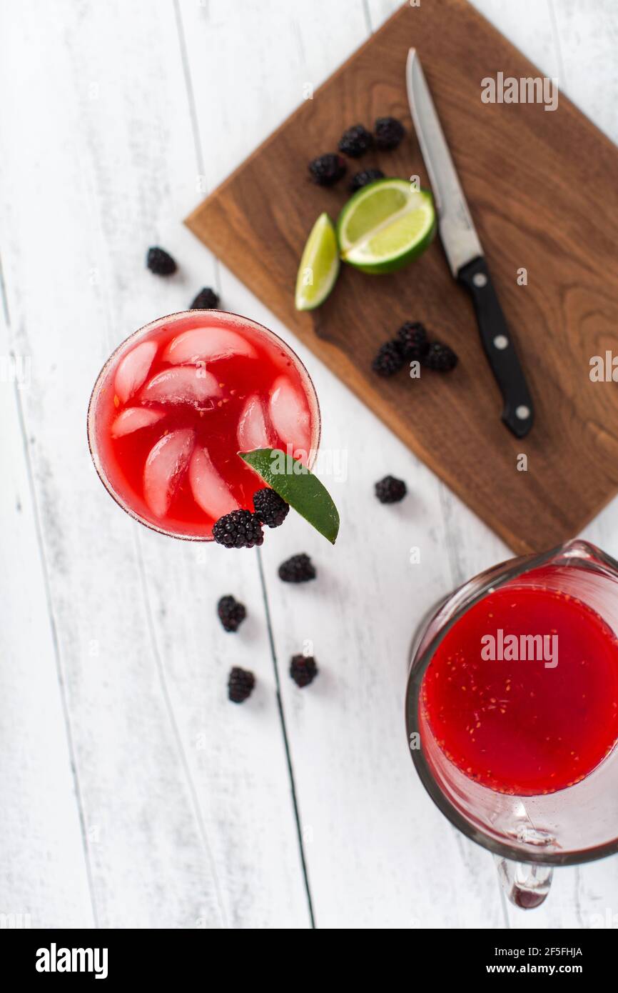 A blackberry berry margarita with fresh blackberries and limes in a margarita glass. Stock Photo
