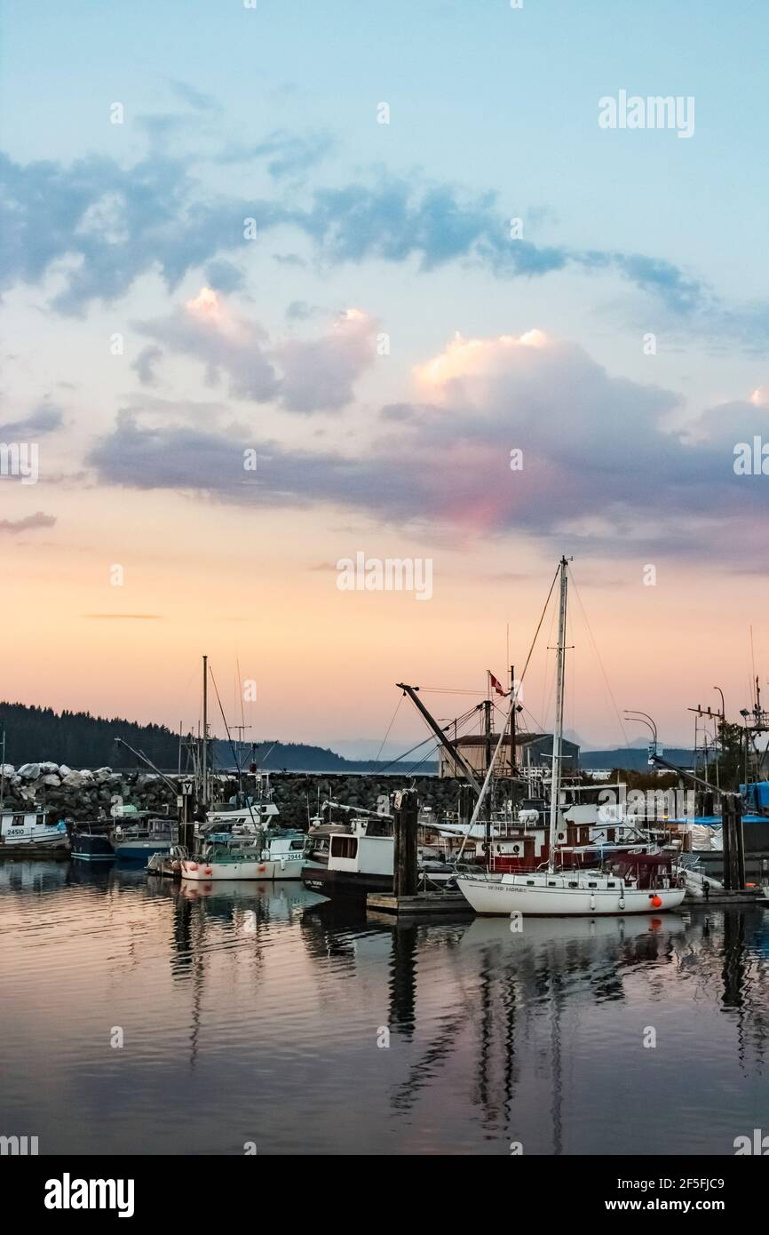 'Pink sky at night, sailor's delight': fishing vessels and pleasure yachts share the docks at Port McNeill, BC, at twilight on a summer evening. Stock Photo