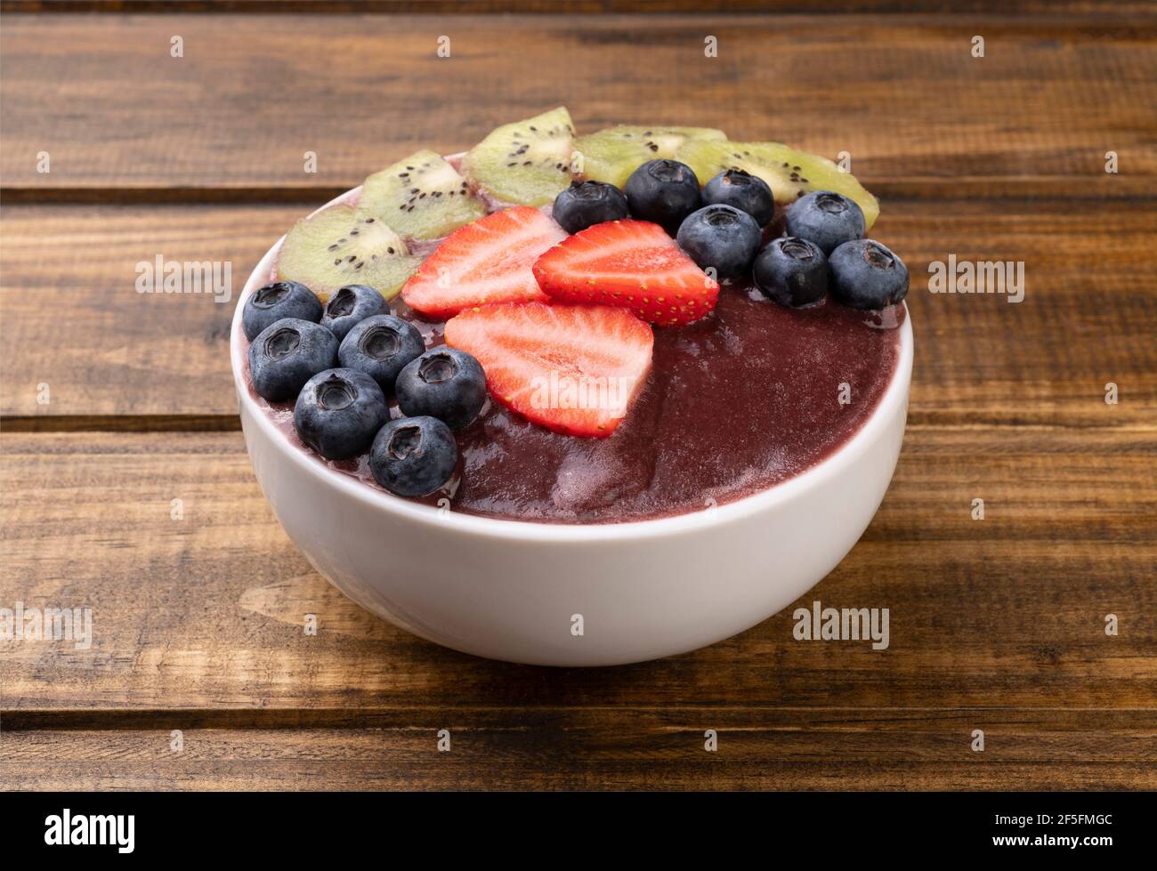 Brazilian typical acai bowl with kiwi, blueberry and strawberry over ...
