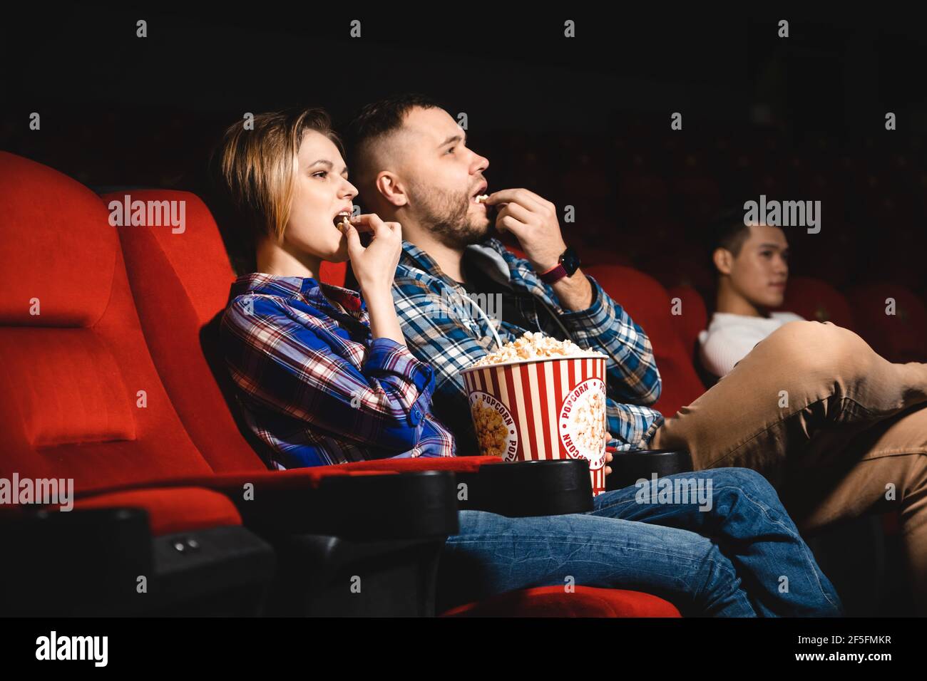 Friends are watching a movie in the cinema. People sit in the armchairs