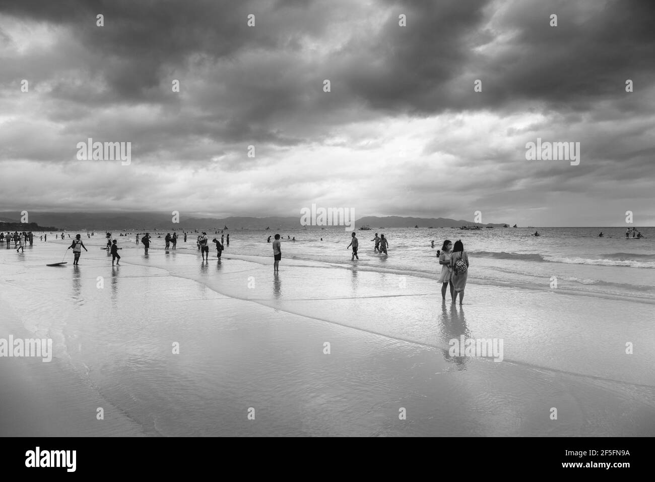 A Group of Tourists At White Beach On A Cloudy Day, White Beach, Boracay, Aklan, The Philippines. Stock Photo