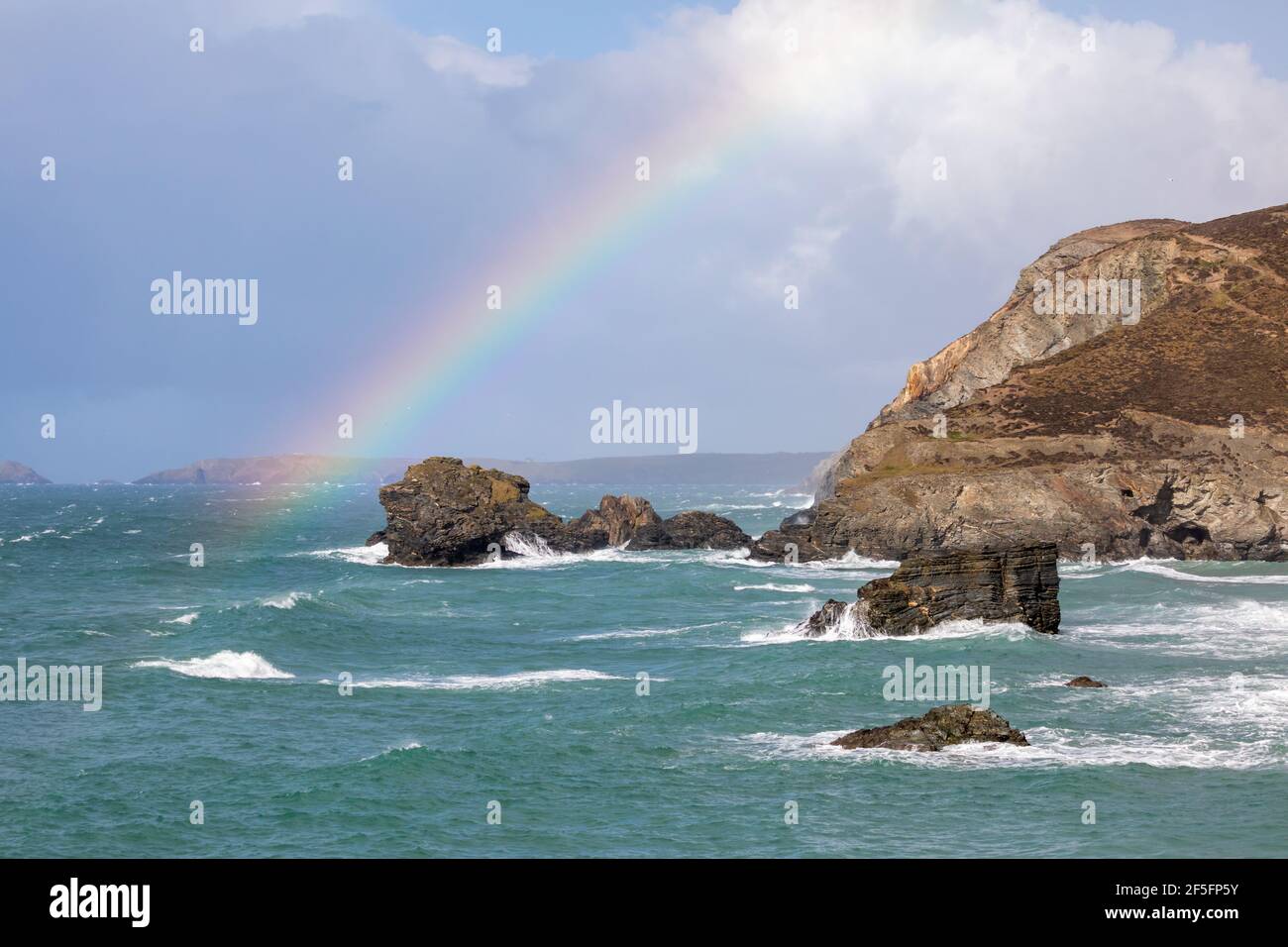 Trevaunance Cove,Cornwall,26th March 2021,After sunshine and showers a colourful rainbow appeared over the sea and cliffs in Trevaunance Cove Cornwall. A seal hung around the cove popping its head out of the water to look around occasionally. Credit: Keith Larby/Alamy Live News Stock Photo