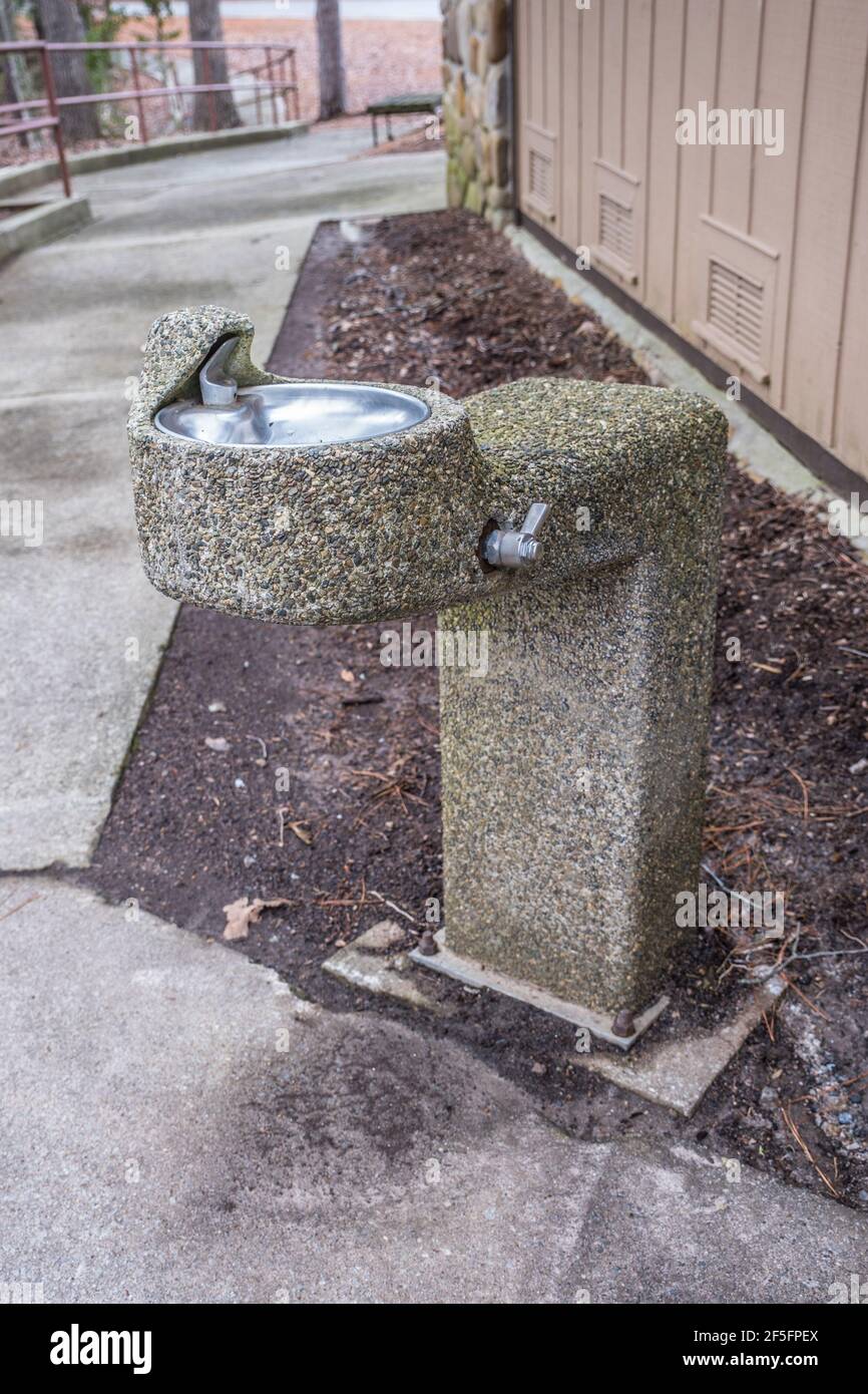 An old worn rustic drinking fountain made of little stones and river