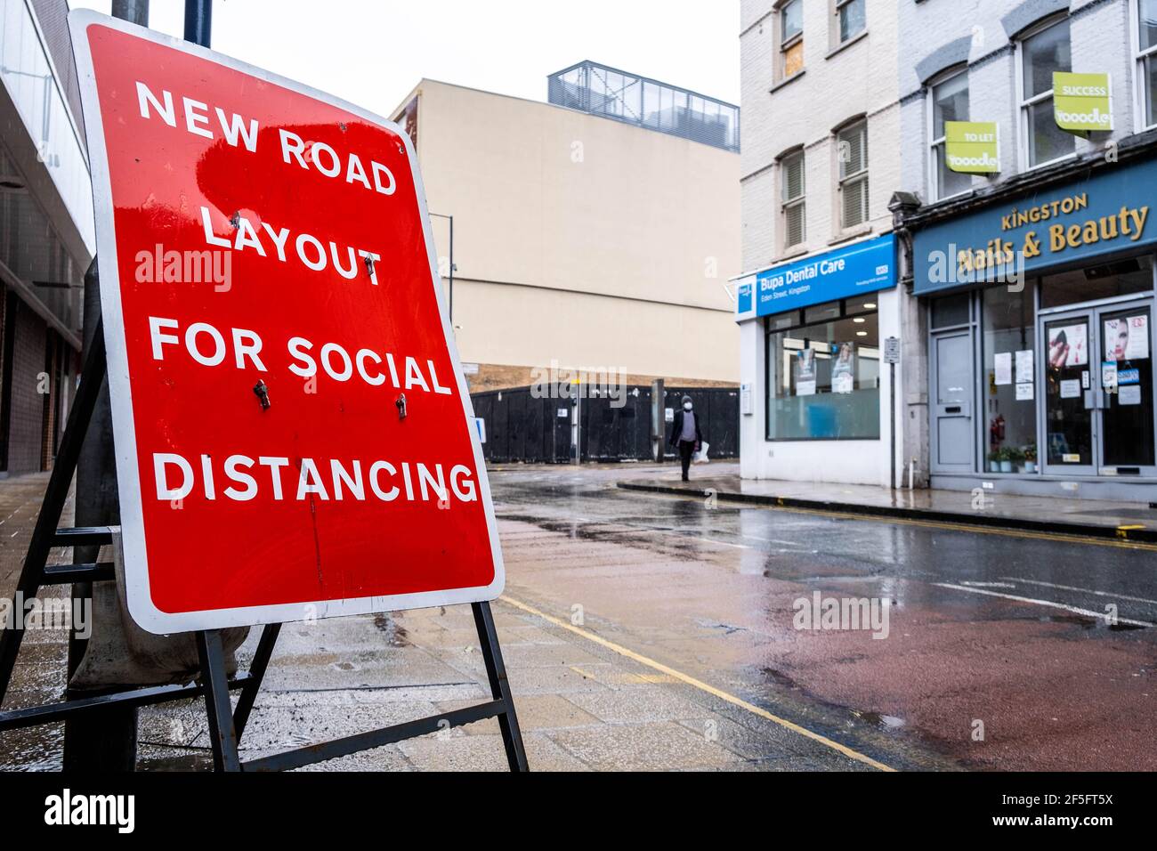 London UK, March 26 2021, Red Road Sign For Social Distancing On An Empty Street With No People On A Wet Raining Day Stock Photo
