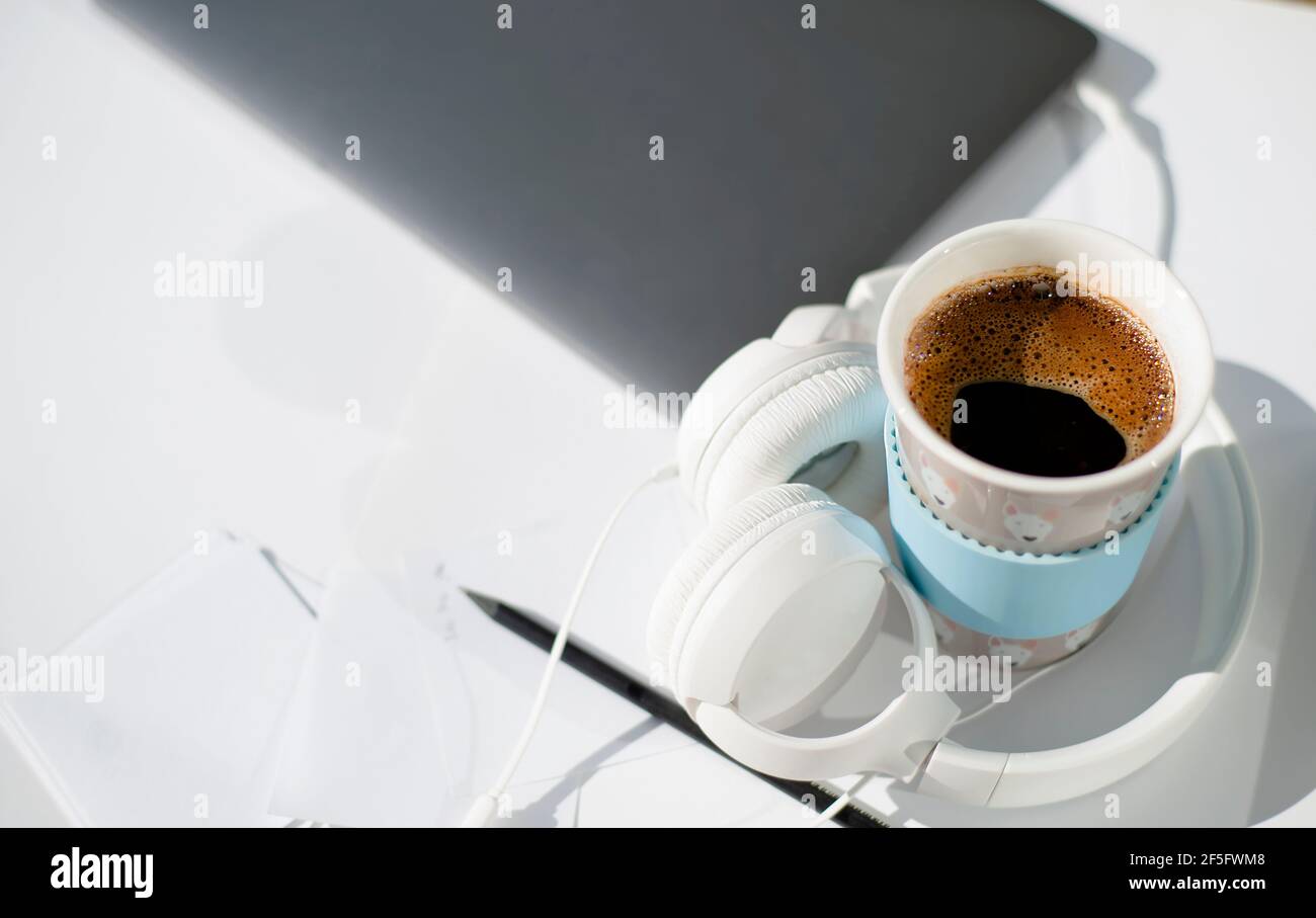 Notebook headphones sheets for writing and a cup of hot coffee on a white background. Copy space. Morning of a modern business person.  Stock Photo
