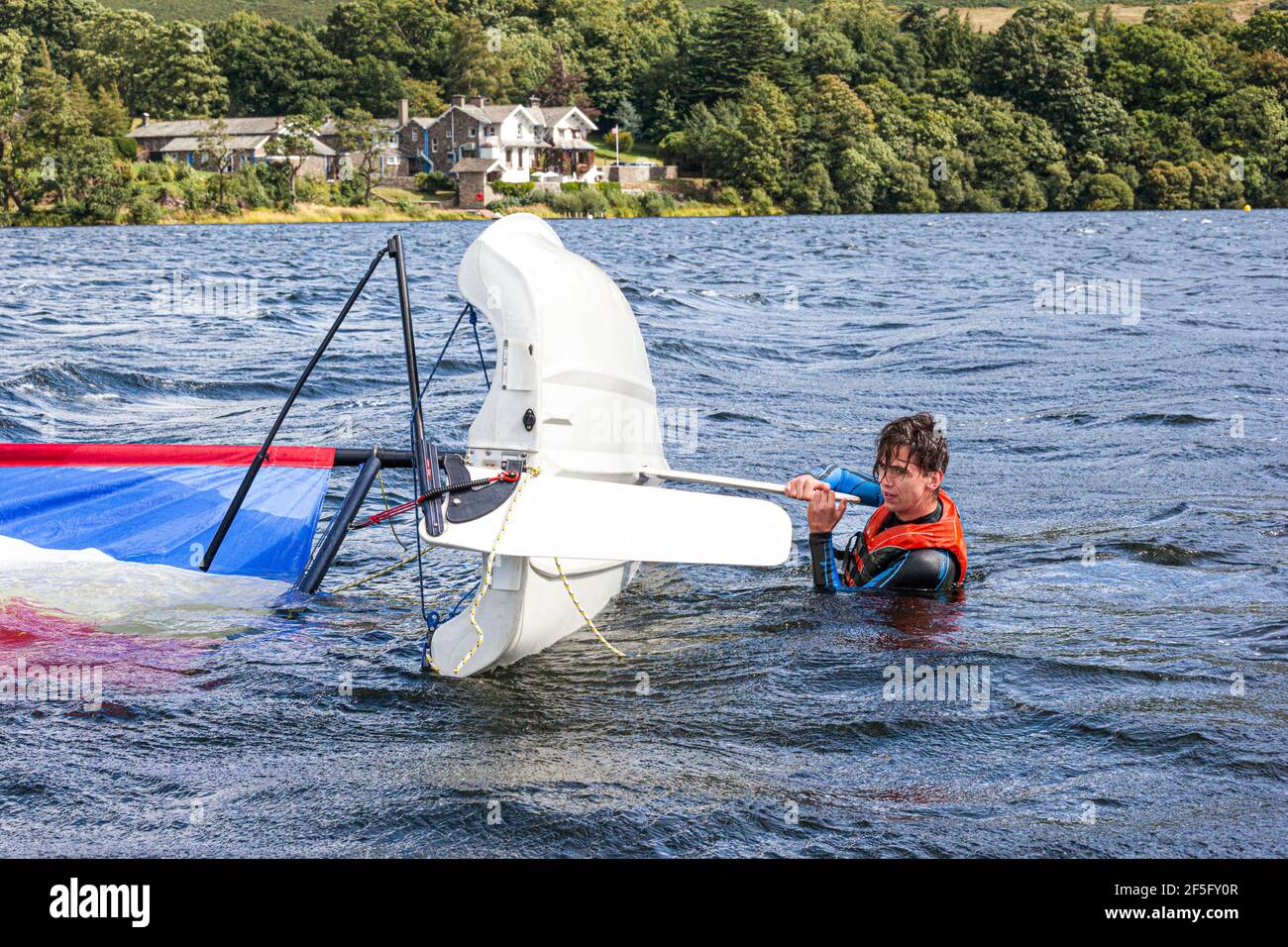 The English Lake District - Sailing on Ullswater, Cumbria UK - A young man about to right a dinghy after capsizing Stock Photo