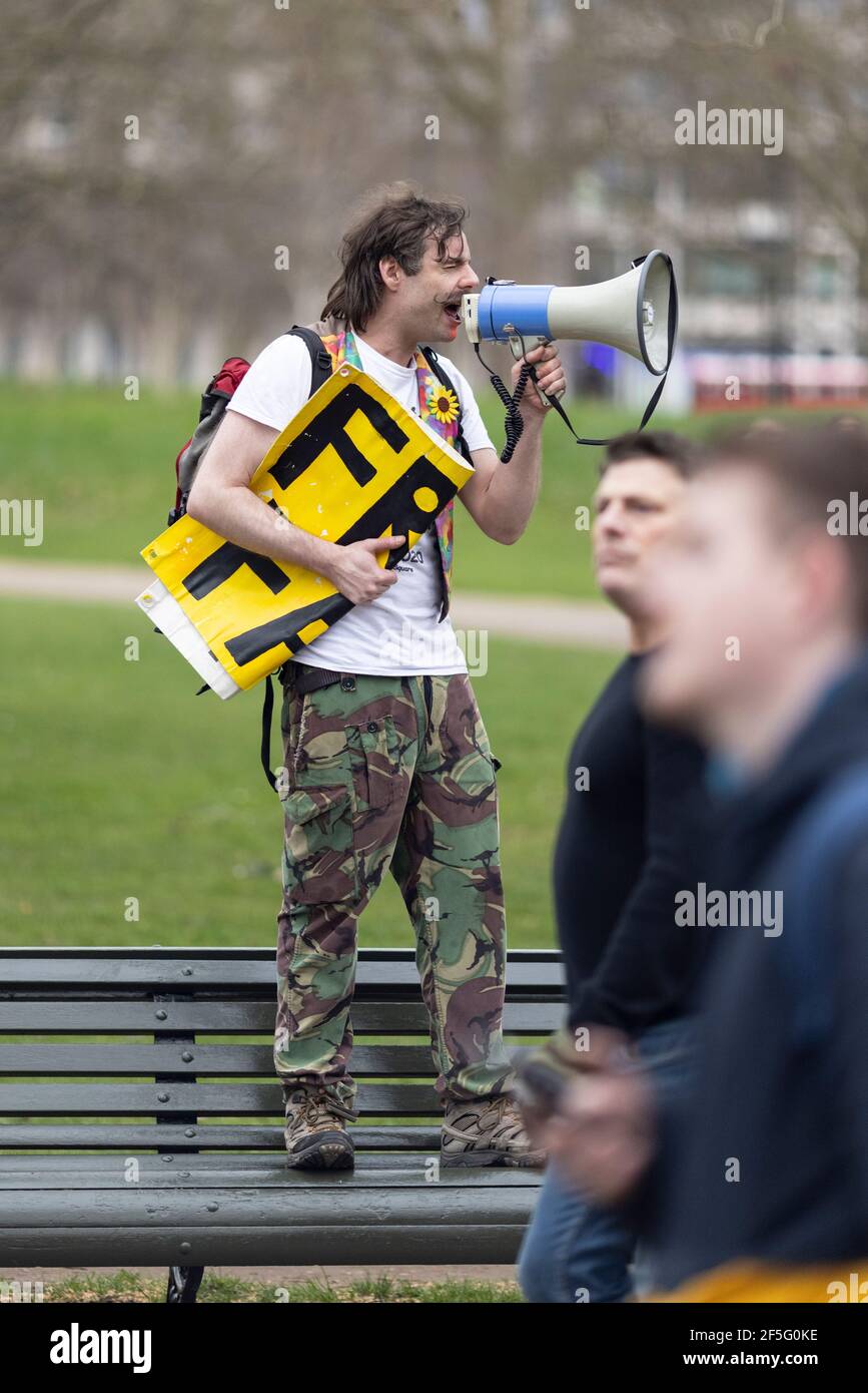 Anti-lockdown and anti Covid-19 vaccination protest, London, 20 March 2021. Man standing on park bench shouting into megaphone. Stock Photo