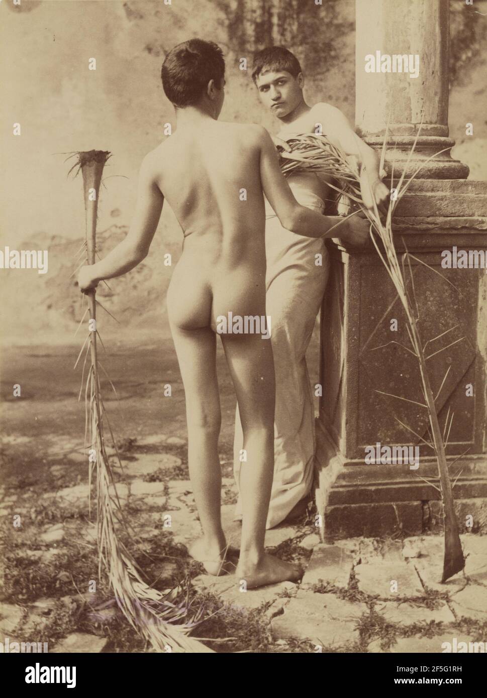 Untitled Two Male Youths Holding Palm Fronds. Baron Wilhelm von Gloeden (German, 1856 - 1931) Stock Photo