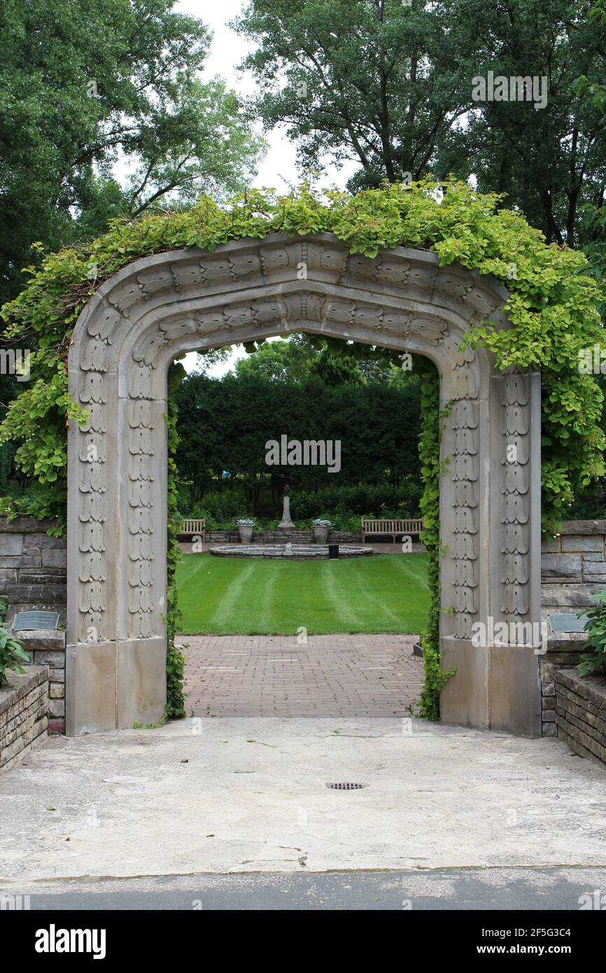 A stone arch entry, covered in a vine, leading to the sunken garden, at ...