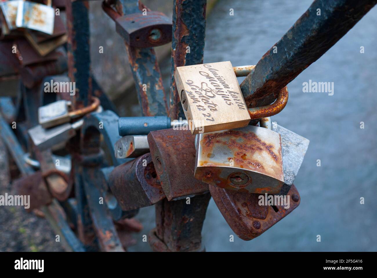 Rusting love padlocks attached to iron railings on bridge over Vilnia River, Vilnius, Lithuania Stock Photo