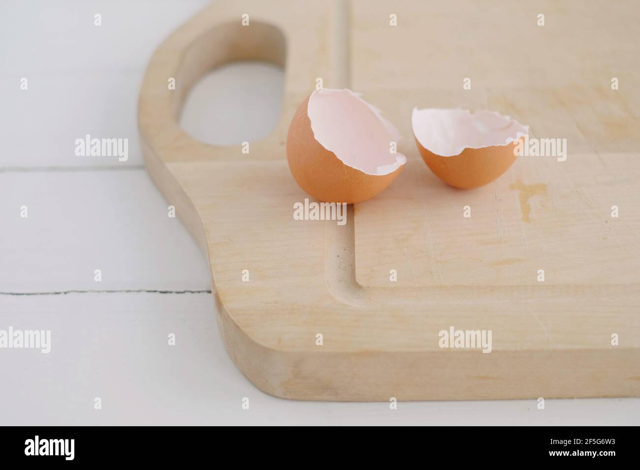 broken eggshells on a wooden light board on a white rustic table Stock Photo