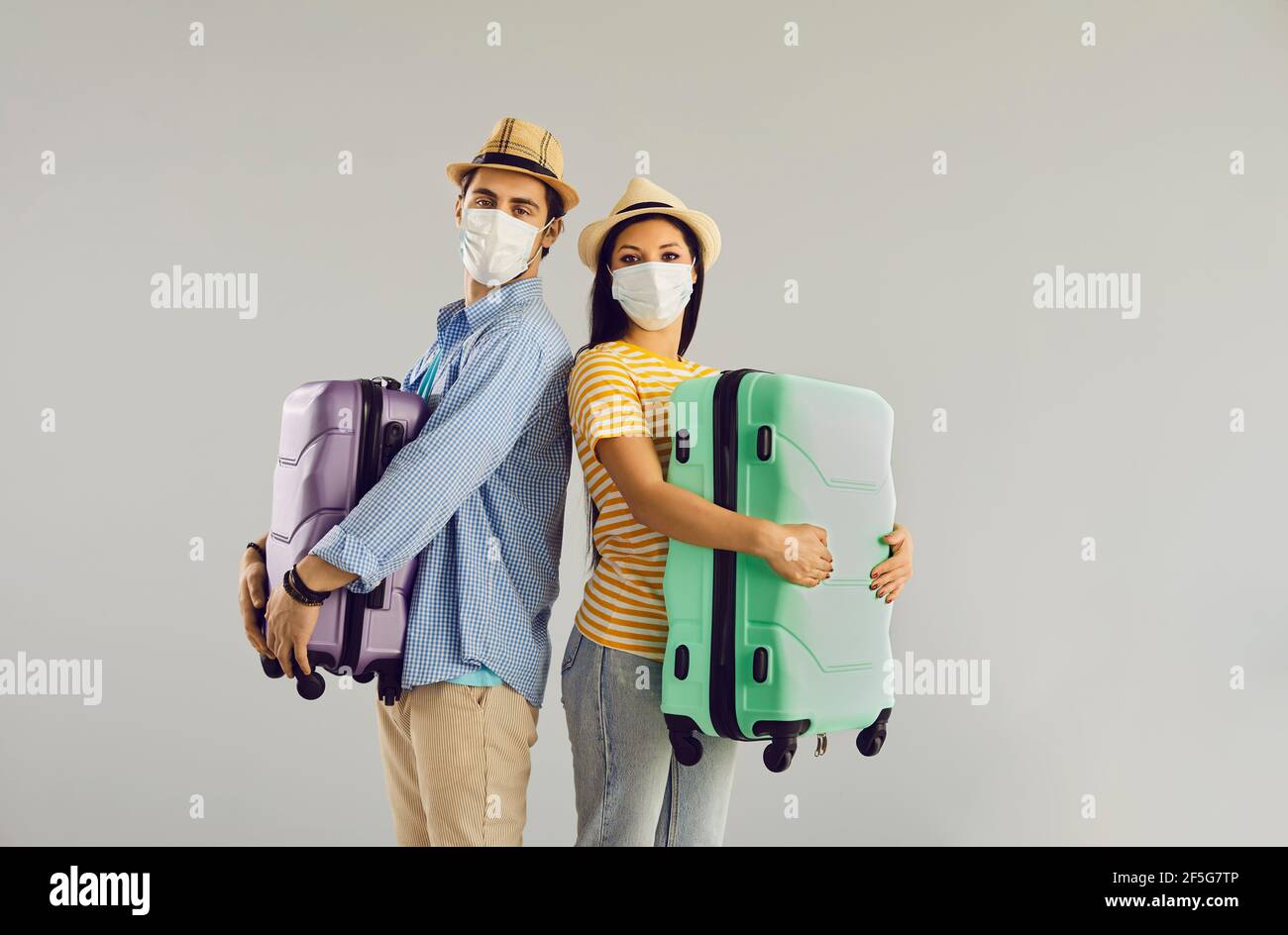 Happy family couple traveler in facial mask with suitcase studio portrait Stock Photo