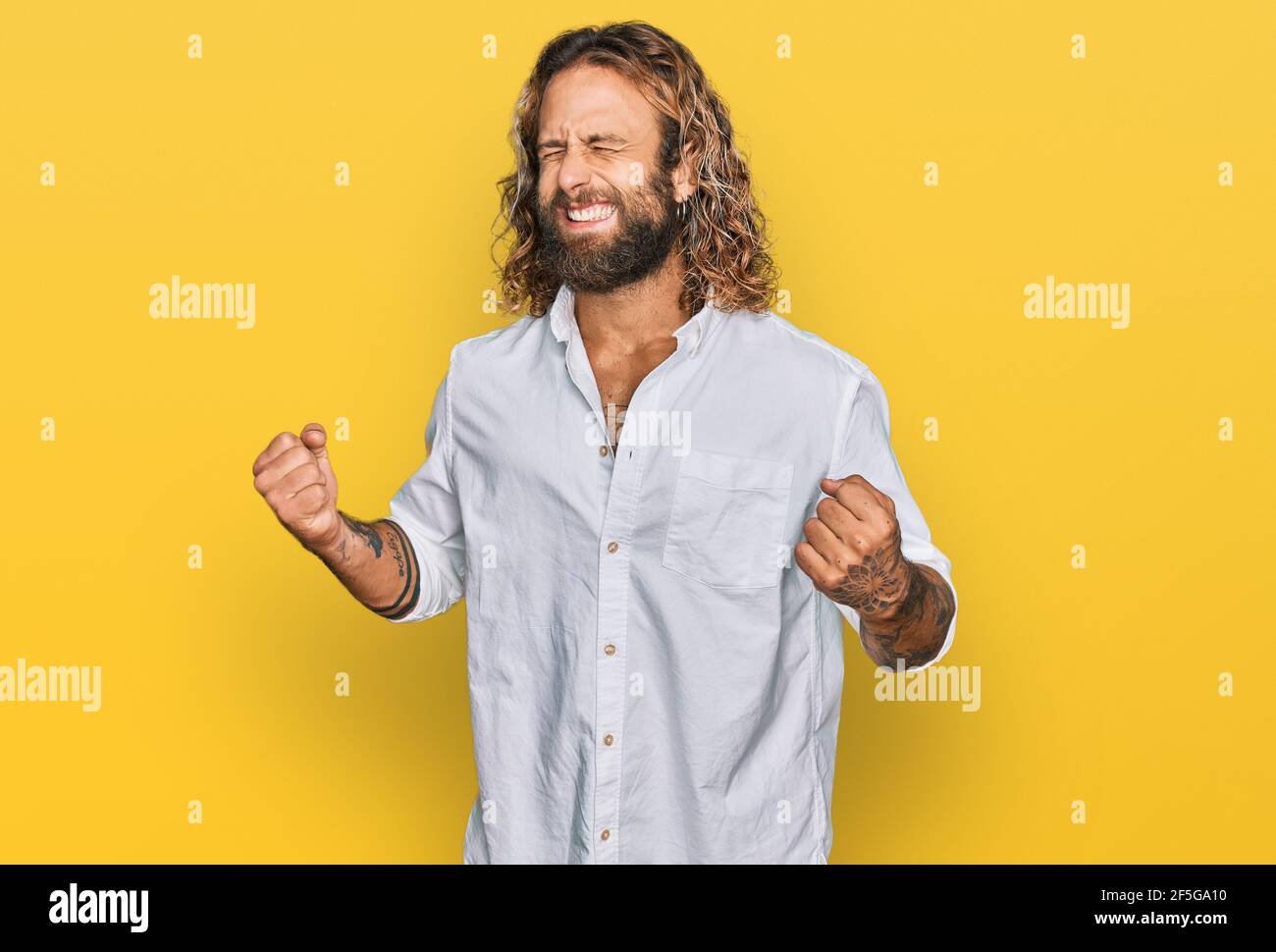 Handsome man with beard and long hair wearing casual clothes excited ...