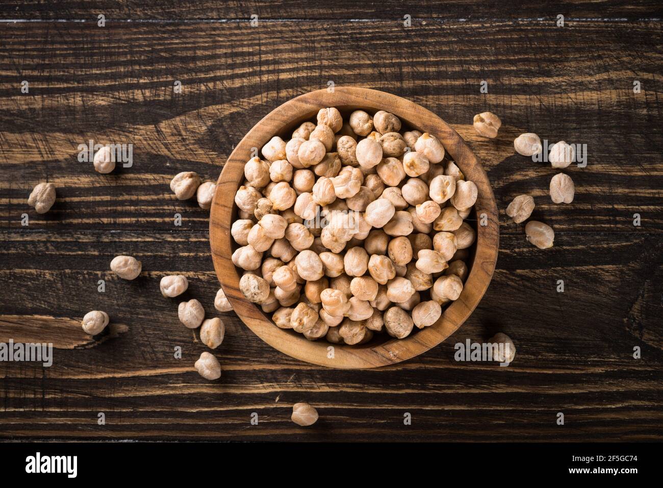 Chickpeas in white bowl at wooden kitchen table. Stock Photo