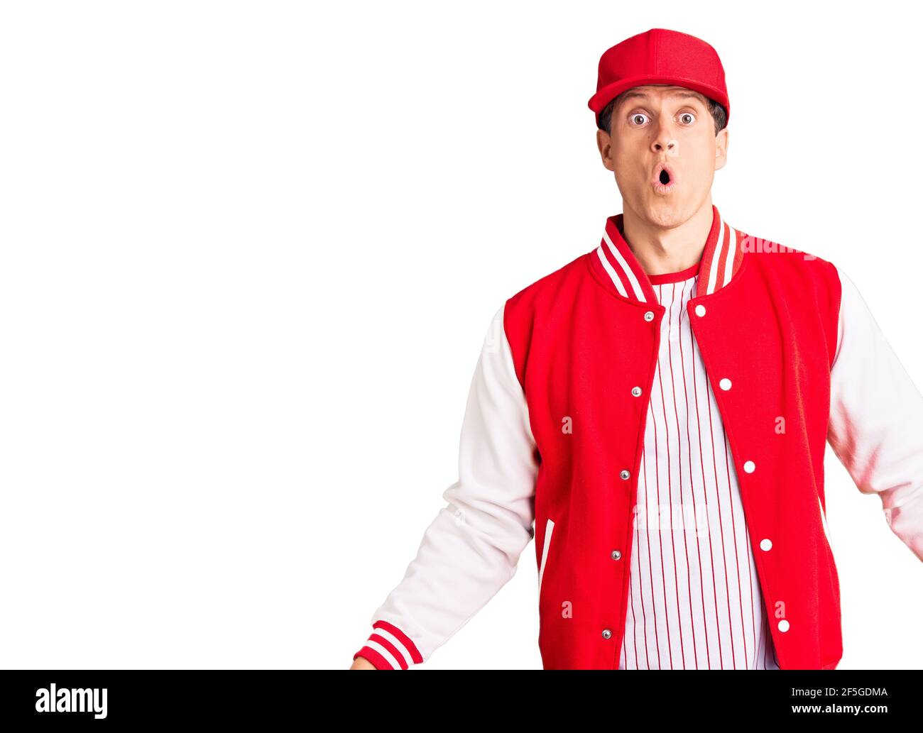 Young handsome man wearing baseball uniform scared and amazed with open mouth for surprise, disbelief face Stock Photo