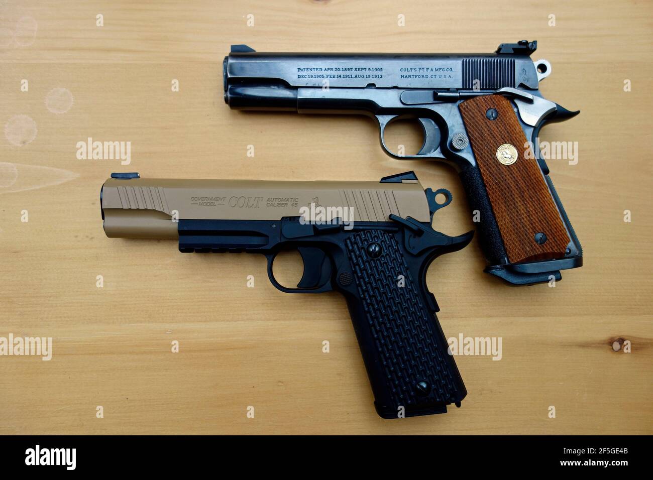 An authentic Colt 45 auto handgun above a replica Colt 45 auto handgun BB pistol Stock Photo