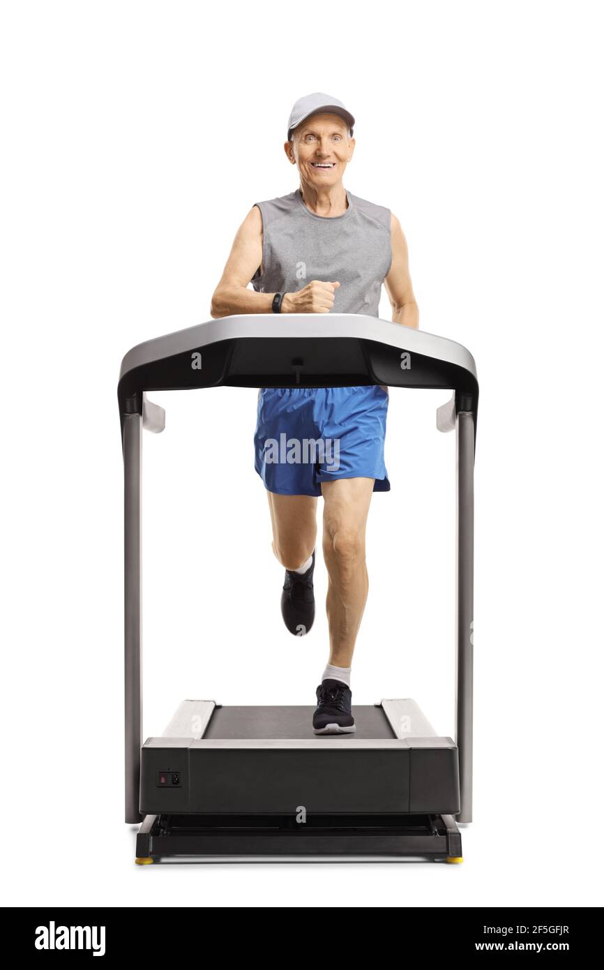 Full length portrait of a smiling elderly man running on a treadmill and looking at the camera isolated on white background Stock Photo