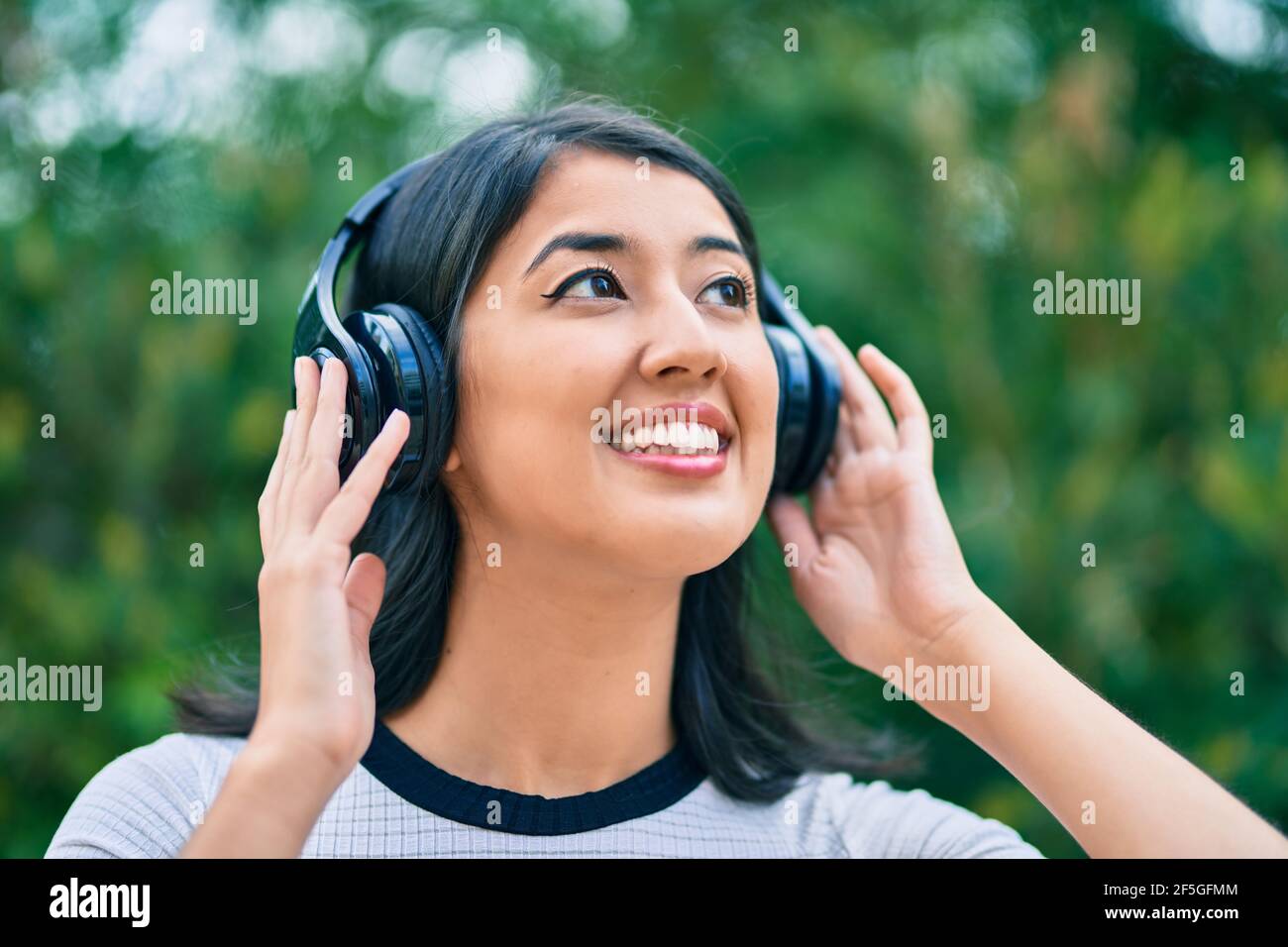 Young hispanic woman smiling happy listening to music using headphones ...