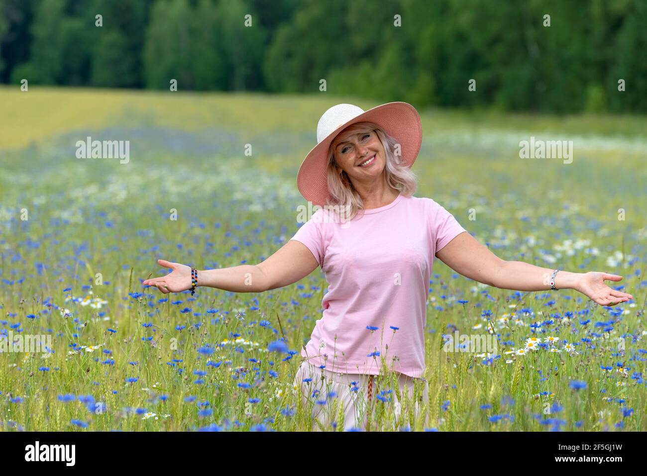 Beautiful middle-aged woman enjoying outdoor activities in the summer, walking through the meadow. Happy, cheerful 55 year old woman leading a healthy Stock Photo