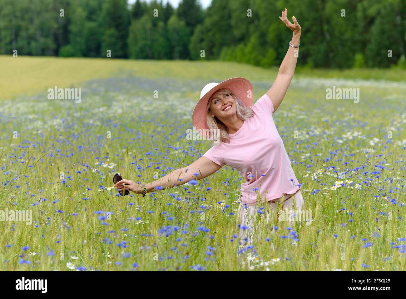 Beautiful middle-aged woman enjoying outdoor activities in the summer, walking through the meadow. Happy, cheerful 55 year old woman leading a healthy Stock Photo