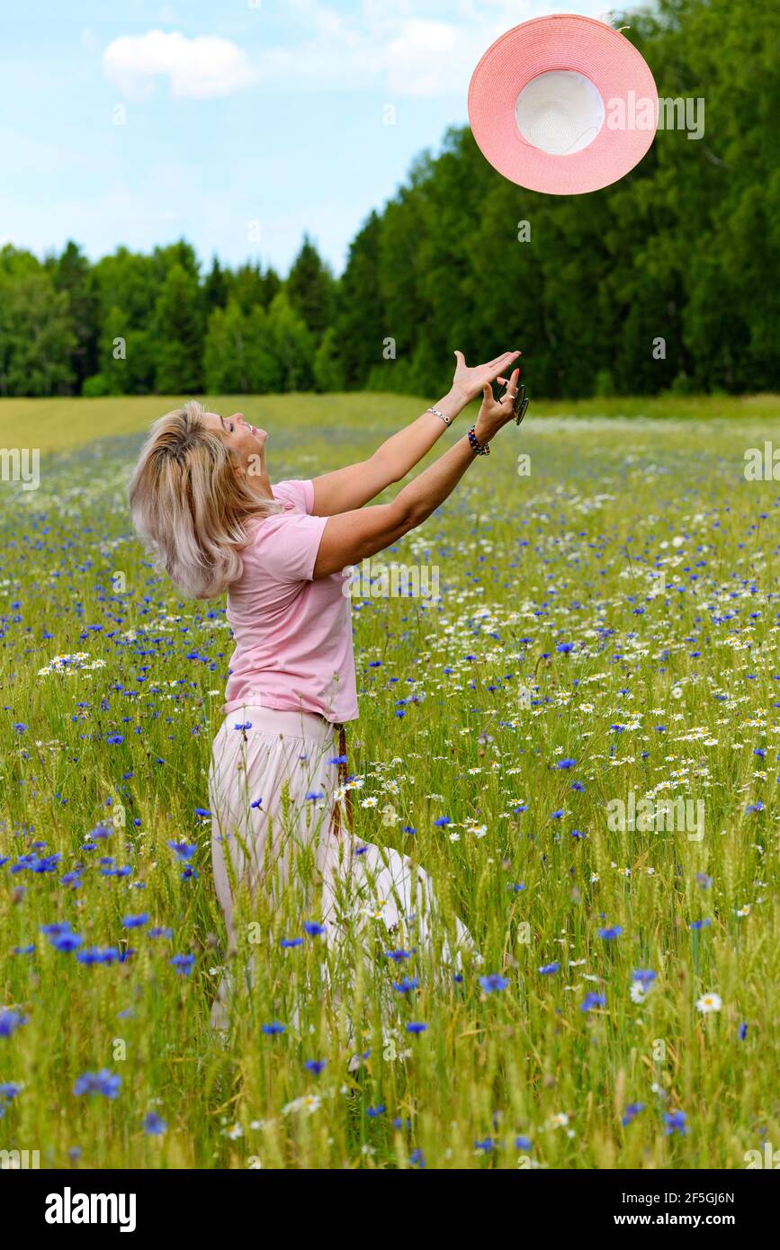 Beautiful middle-aged woman enjoying outdoor activities in the summer, walking through the meadow. Happy, cheerful 55 year old woman leading a healthy Stock Photo