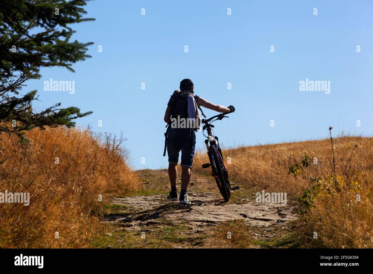Cyclist pushing a bike uphill Stock Photo