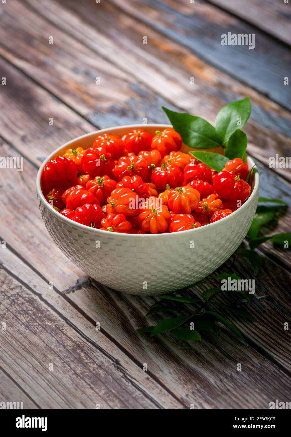 Surinam cherry in a white bowl on a wooden table. Stock Photo