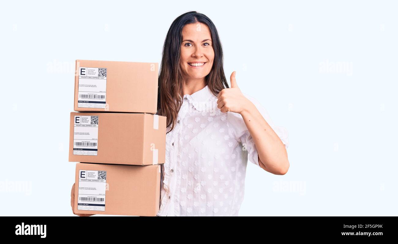 Young beautiful brunette woman holding delivery cardboard package ...