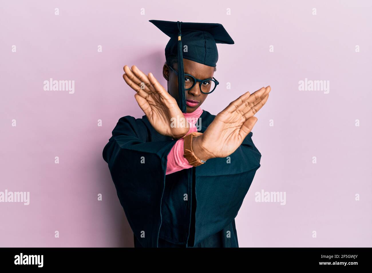 Young african american girl wearing graduation cap and ceremony robe rejection expression crossing arms and palms doing negative sign, angry face Stock Photo
