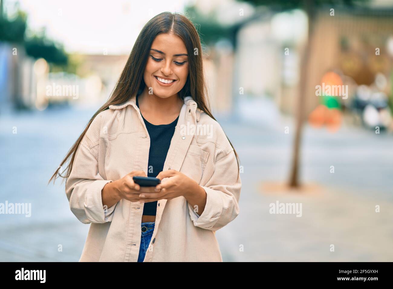 Young hispanic girl smiling happy using smartphone at the city Stock ...