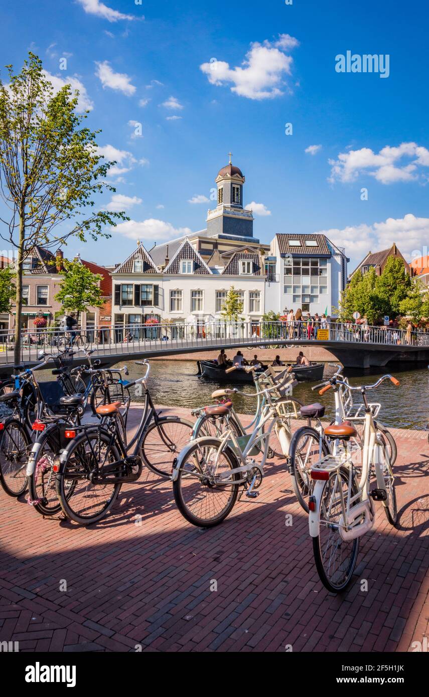 Bunch of bicycles standing by a canal next to a bridge in Leiden, the Netherlands Stock Photo