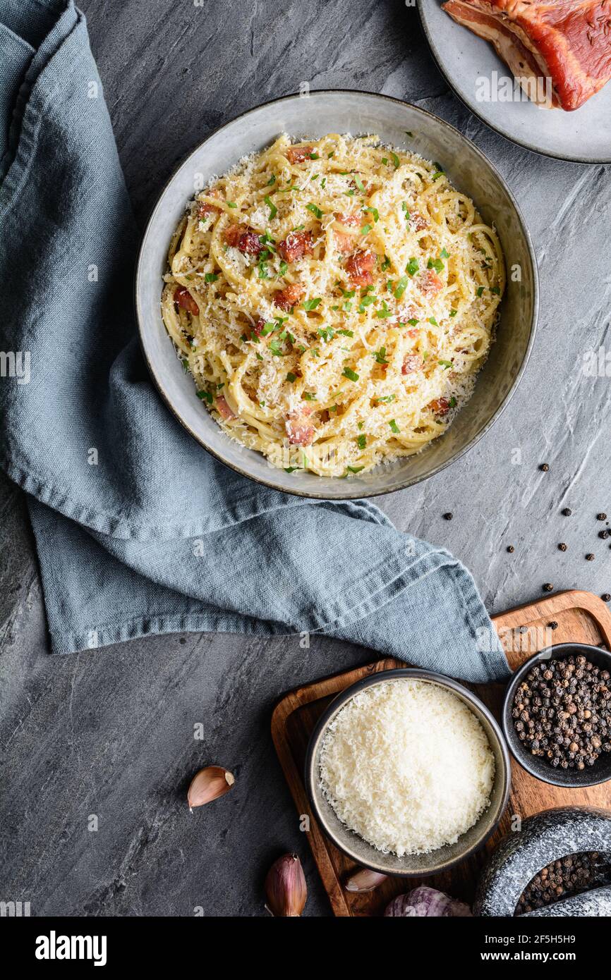 Classic pasta Carbonara in a ceramic plate, hearty Italian dish made with Spaghetti, egg, fried bacon, topped with grated Parmesan cheese and black pe Stock Photo