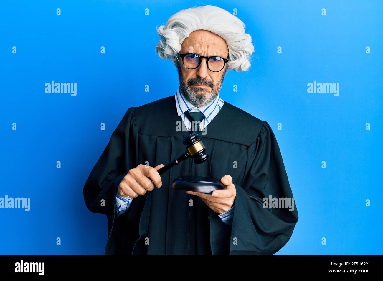 Middle age hispanic man using gavel depressed and worry for distress, crying angry and afraid