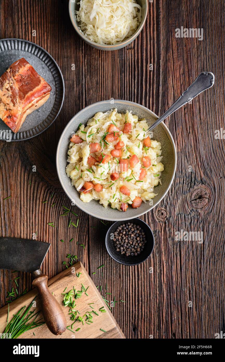 Kapustove halusky known as Strapacky, classic dish in Slovakia, boiled potato dumplings with sauerkraut and onion, topped with fried bacon and fresh c Stock Photo