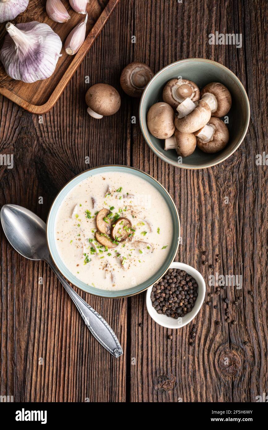Delicious lunch, comforting Cream of mushroom soup topped with freshly chopped chives on rustic wooden background Stock Photo