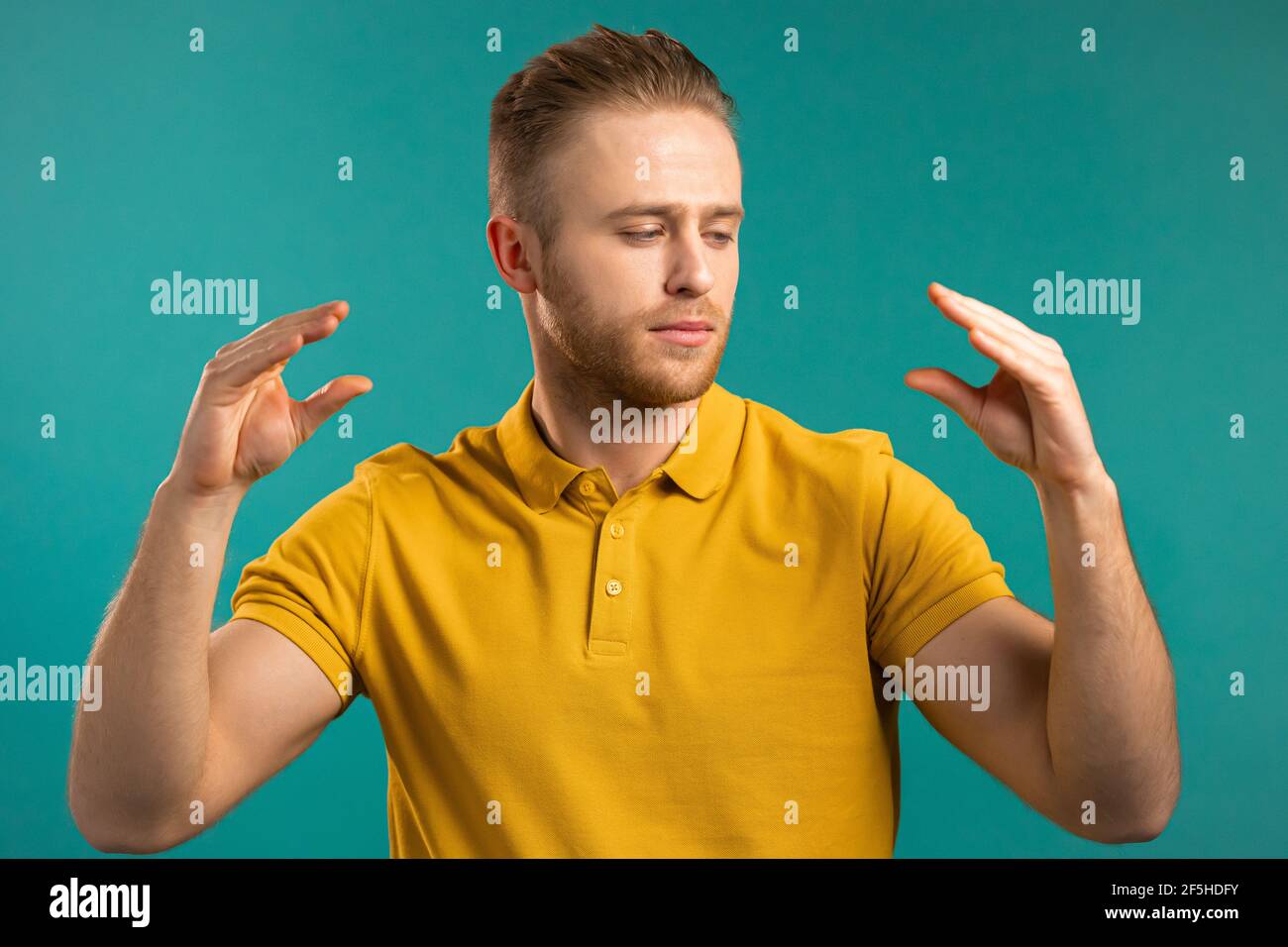 Handsome bored man showing bla-bla-bla gesture with hands isolated on blue background. Empty promises, blah concept. Lier Stock Photo