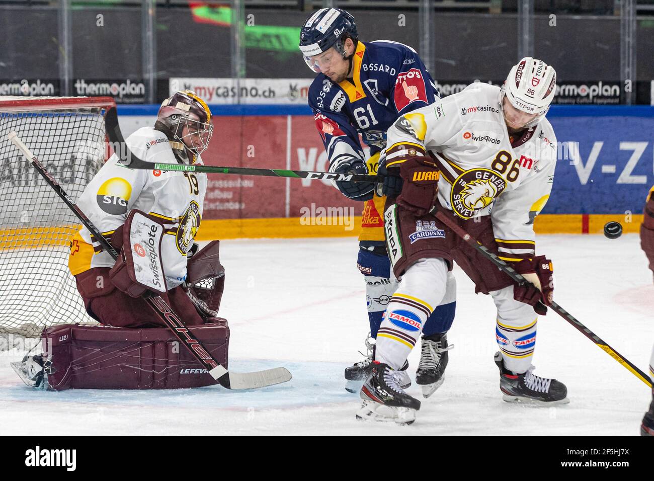 # 86 Joel Vermin (Geneva) with Sven Leuenberger # 61 (EV Zug) fighting for the disc during the National League Regular Season ice hockey game between EV Zug and Geneve-Servette HC on March 24th, 2021 in the Bossard Arena in Zug. (Switzerland/Croatia OUT) Credit: SPP Sport Press Photo. /Alamy Live News Stock Photo