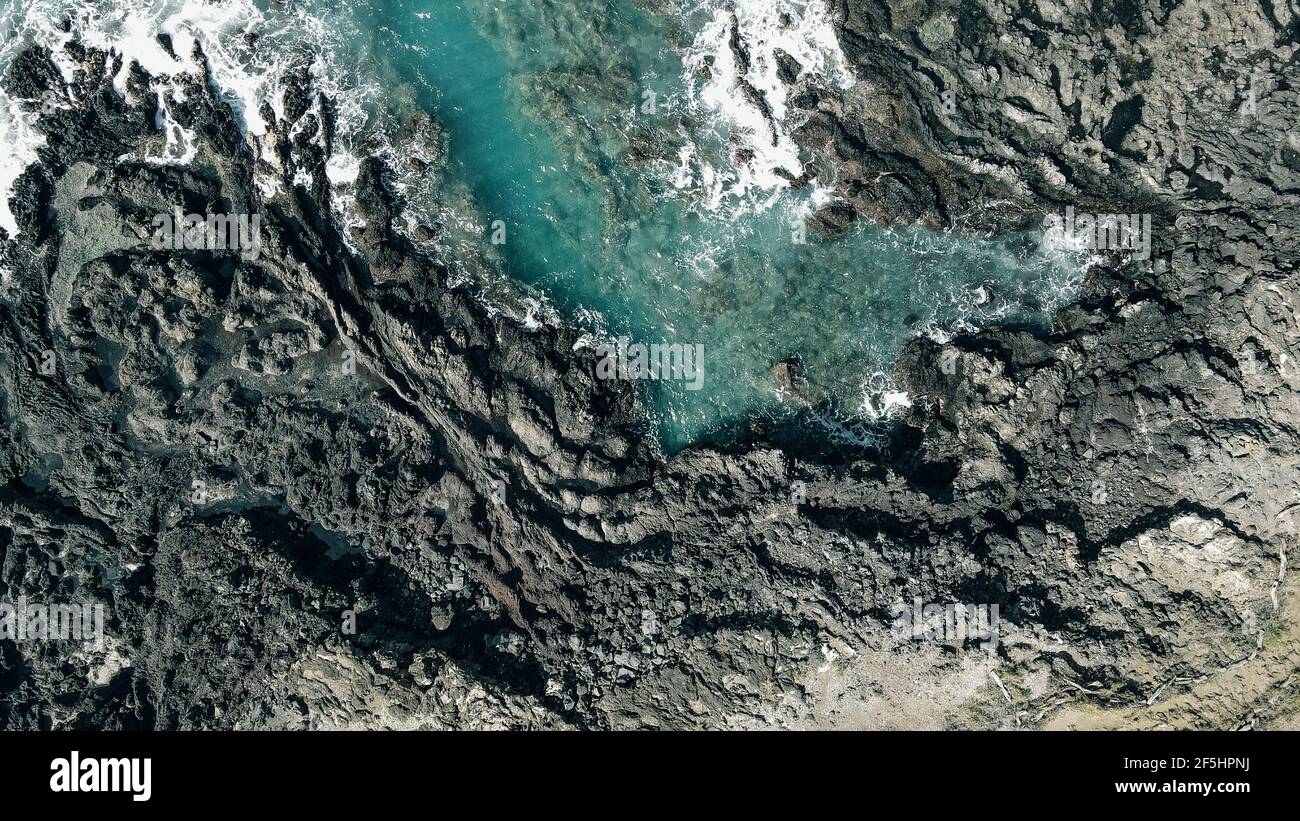 Aerial shot of waves crashing into a Hawaiian lava rock coast. drone ...