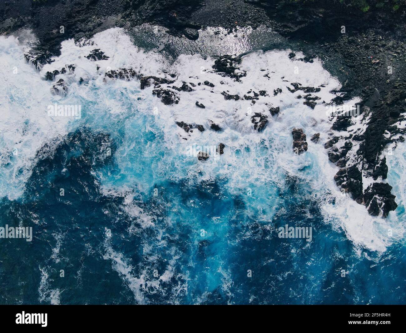 Aerial shot of waves crashing into a Hawaiian lava rock coast. drone ...