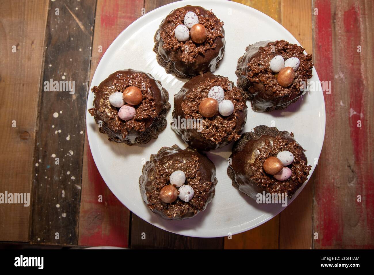 A selection of Easter Chocolate nest Cakes topped with three little chocolate mini eggs on a white plate Stock Photo