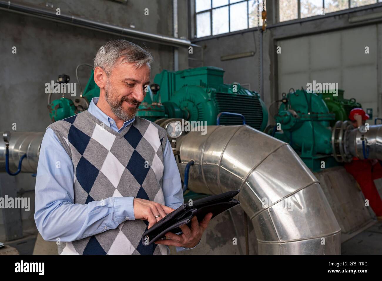 Business Person Using Digital Tablet Inside Factory Hall. Engineer Standing in District Heating Power Plant. Digital Technology Concept. Industry 4.0 Stock Photo