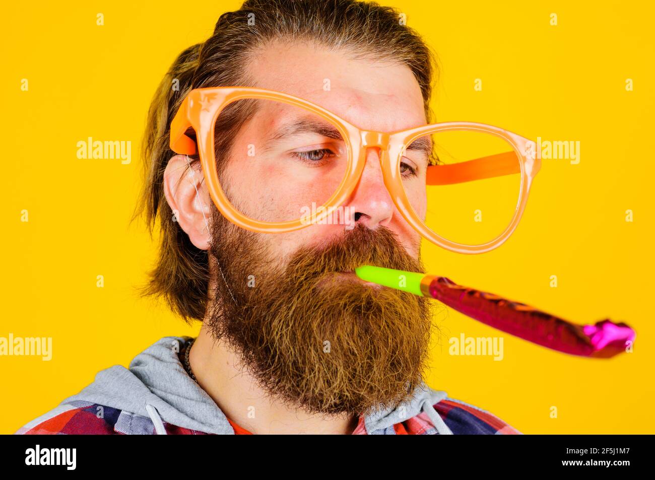 Handsome man with party horn blower. People, birthday and celebration concept. Stock Photo