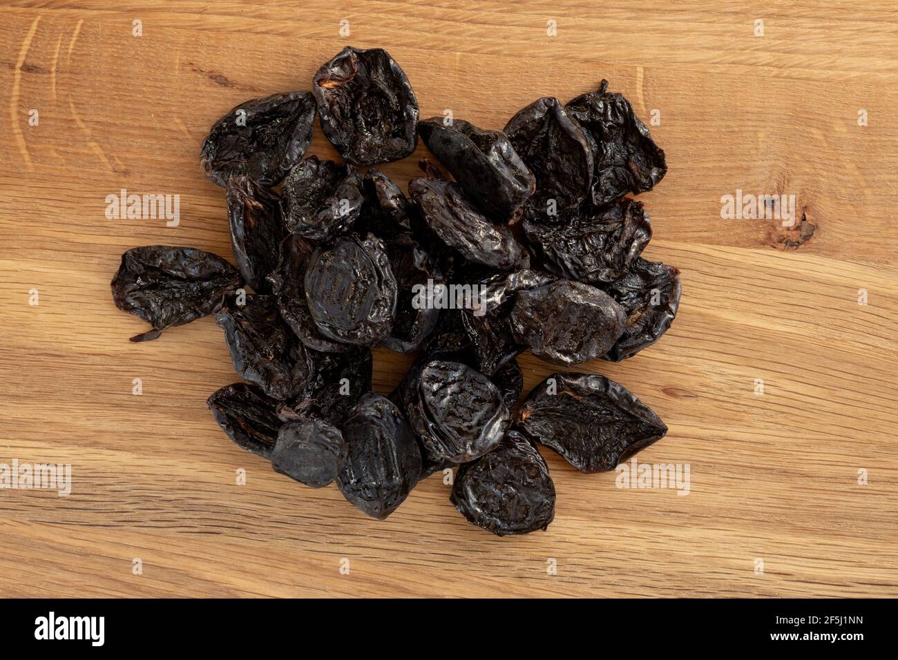 Pile of prunes, dry plums isolated on wood background. Heap of dried fruits. Stock Photo