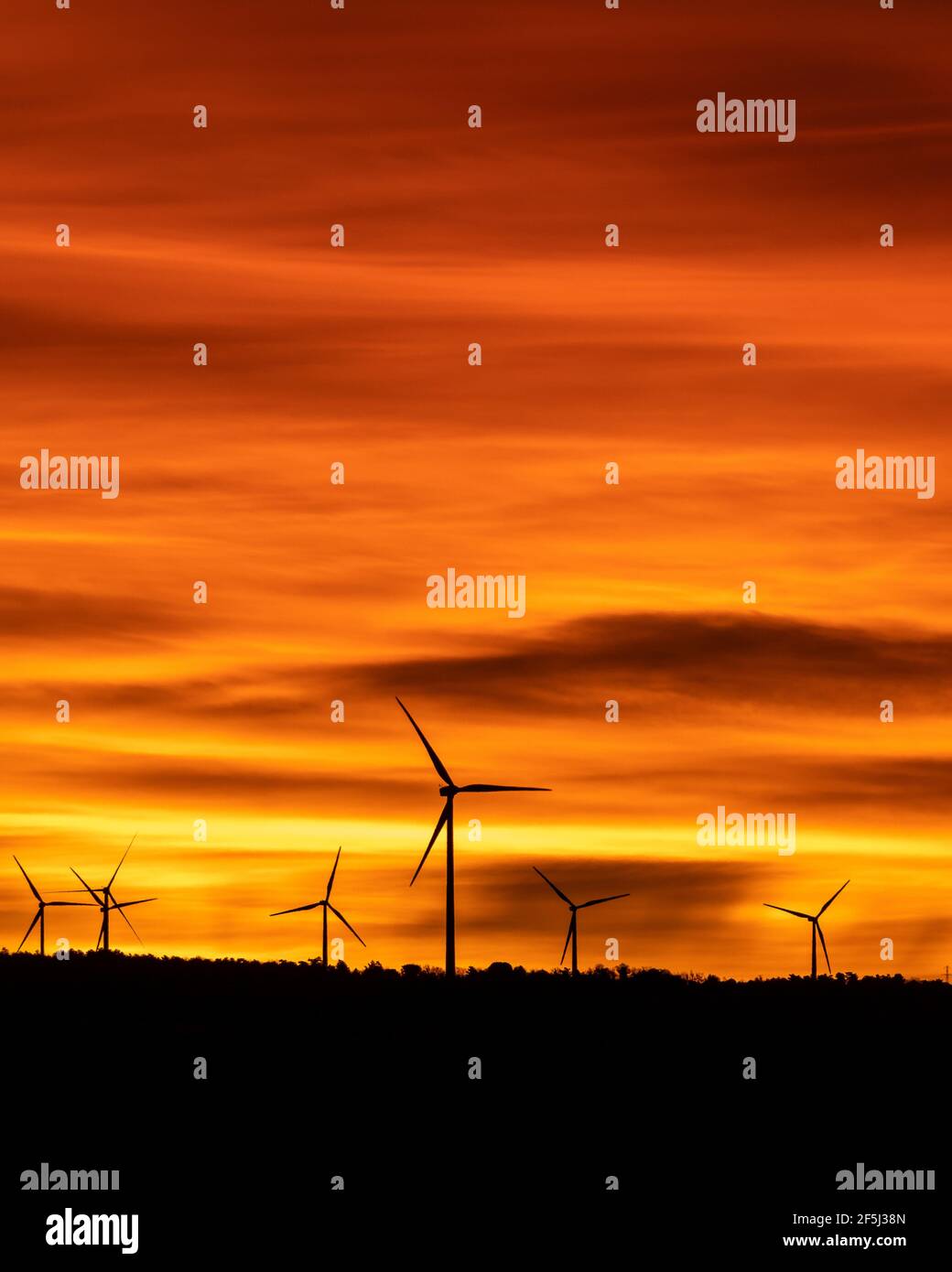 silhouettes of wind turbines in a cloudy, orange sunset Stock Photo - Alamy