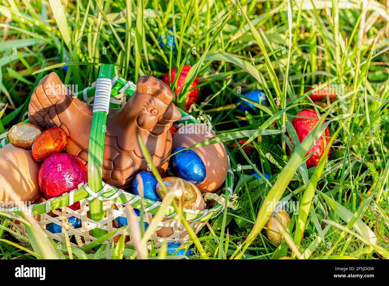 Easter. Chocolate hen and Easter eggs, in a basket on the grass Stock Photo