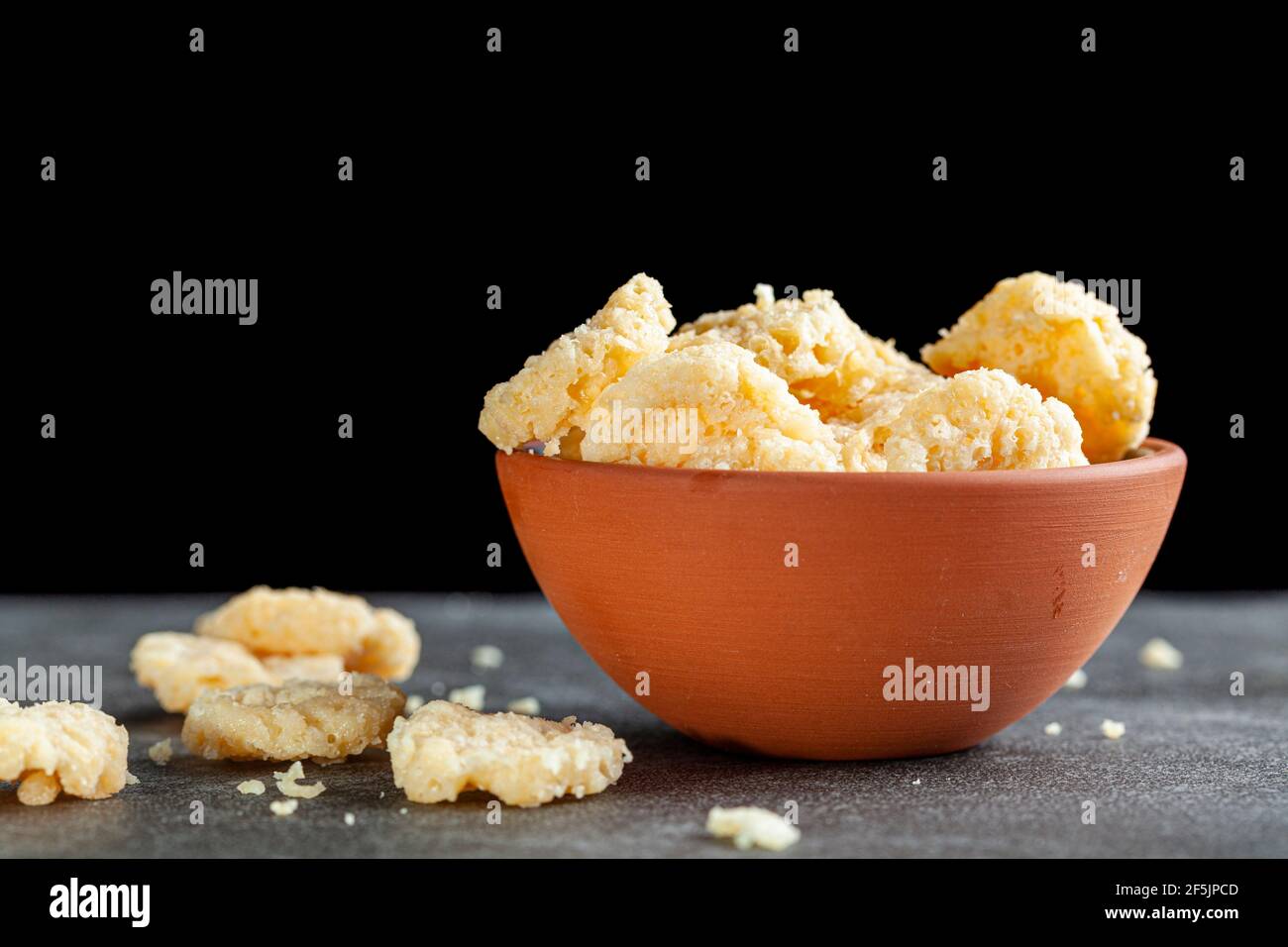Oven baked cheese bites in a terra cotta cup against dark background. These crunchy delicious snacks are good for nibble also for  added flavor in sou Stock Photo