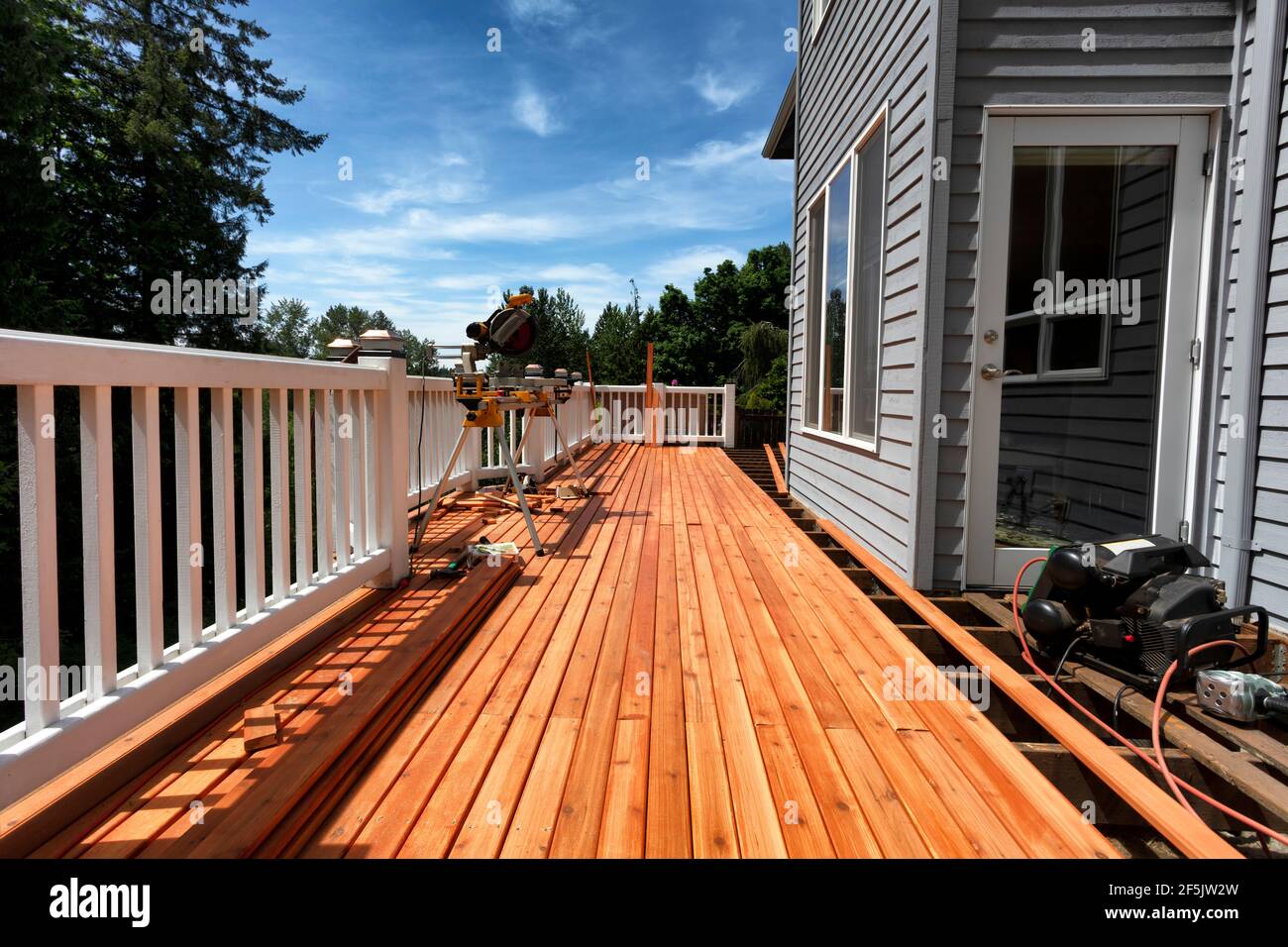 Complete home outdoor deck remodel with new red cedar wood planks being installed Stock Photo