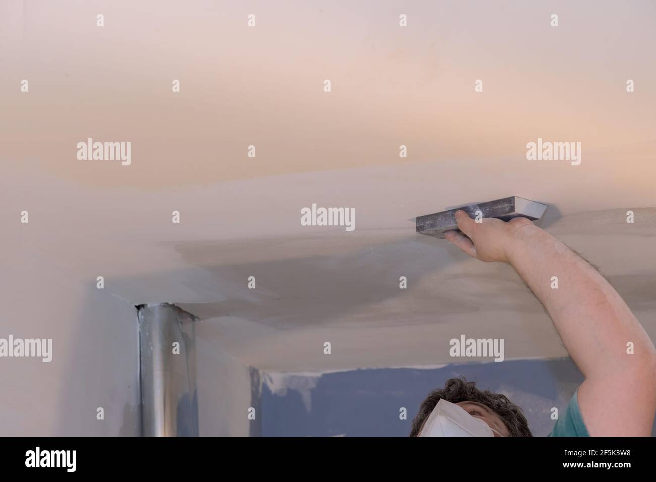 Worker sanding the drywall mud using sand trowel during renovation the