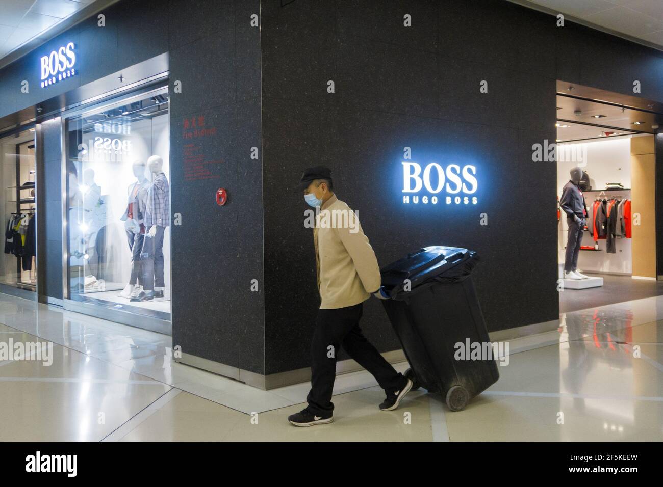 A mall employee pulls a bin past a store of German fashion house Hugo Boss  in Beijing, China, March 27, 2021. REUTERS/Thomas Peter Stock Photo - Alamy