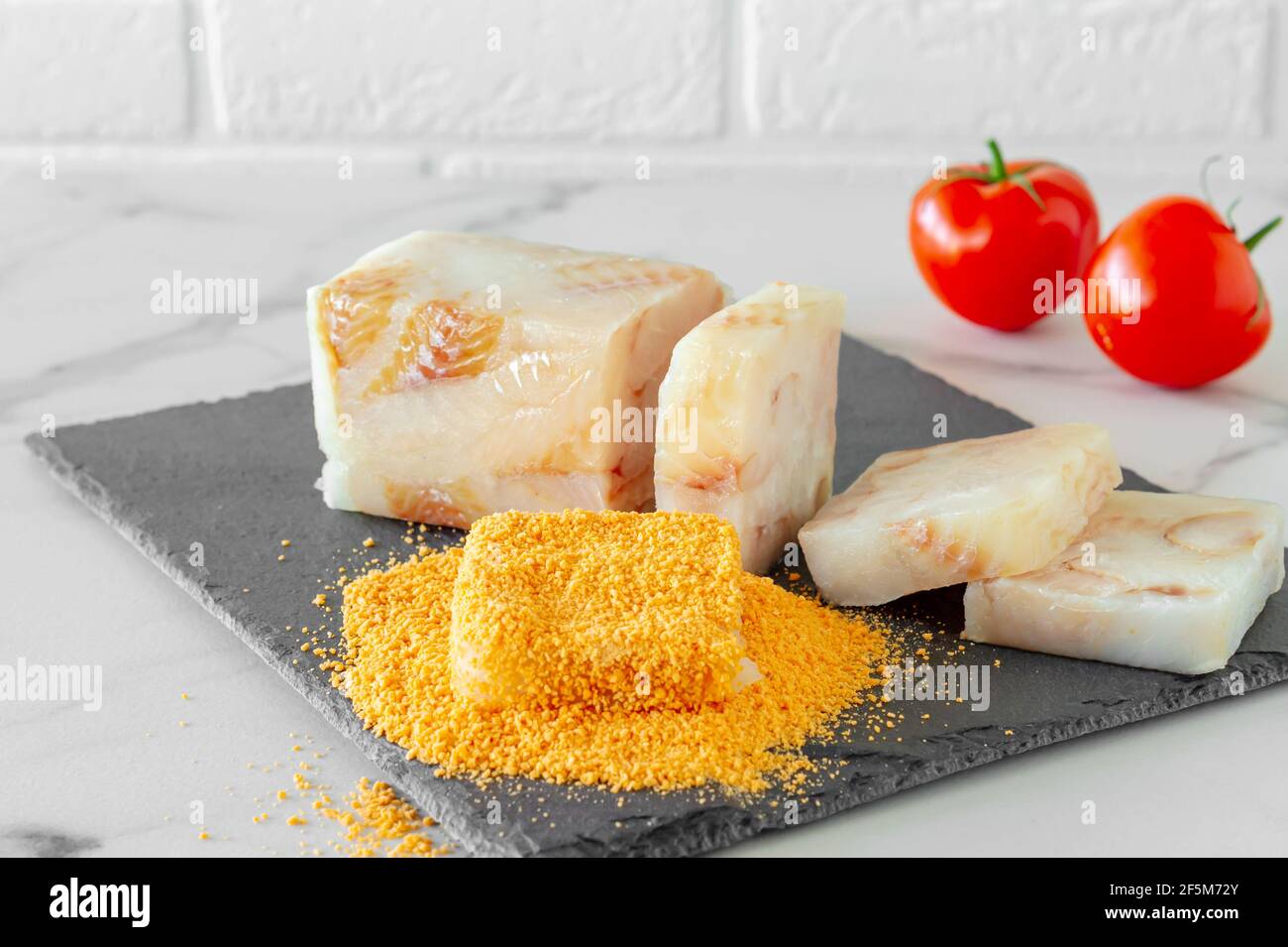 Raw fish blocked in crumbs on a stone board prepared for frying. Stock Photo